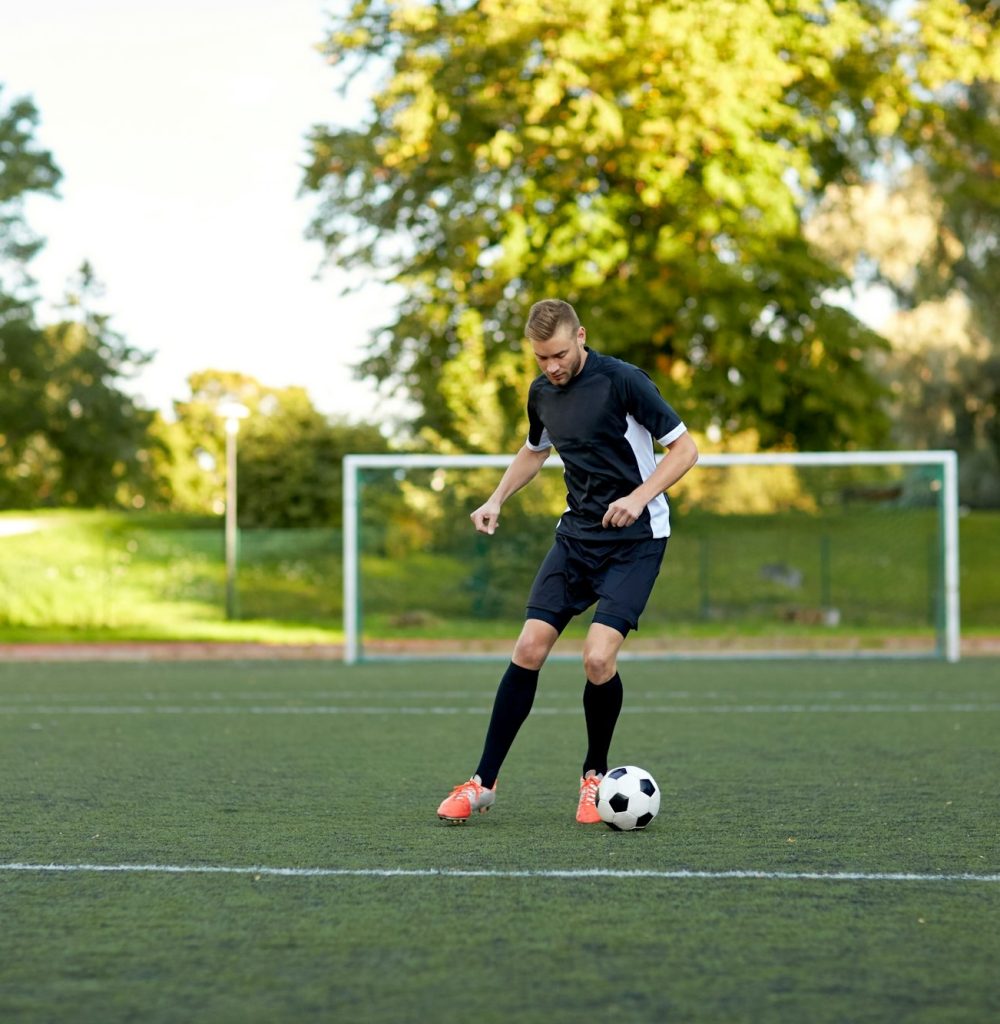 soccer player playing with ball on football field